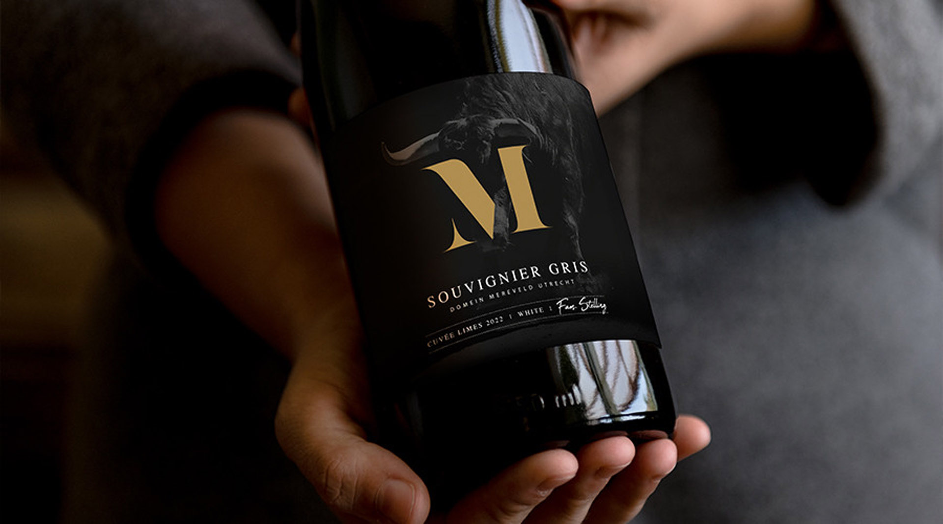 Fles Mereveld Souvenir Gris wijn wordt stijlvol gepresenteerd in de hand.